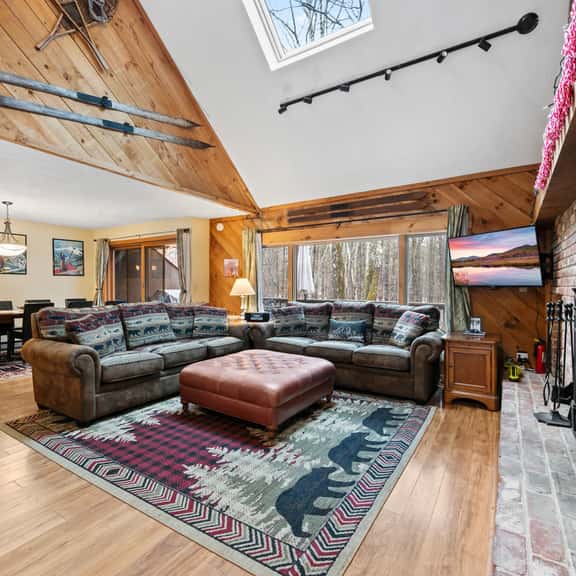 Rustic great room with skylight, wood stove, and forest-view windows.